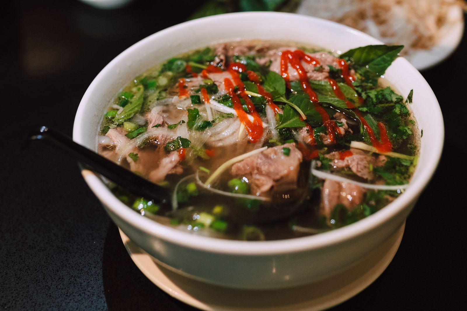 Pho with chilli sauce on a dark table